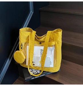 Detail of yellow nylon tote bag with transparent pocket on dark wooden stairs