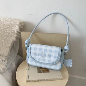 Detail of blue plaid underarm bag with cute embroidery and a cookie-shaped charm