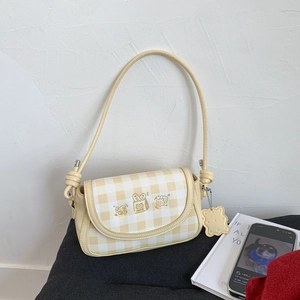 Close-up of yellow checkered shoulder bag with cute cartoon embroidery and biscuit charm