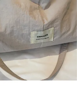 Close-up of beige canvas tote bag with crinkled nylon texture and rectangular brand label