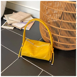 Detail of yellow pleated leather pillow bag with silver sphere zipper pull on marble