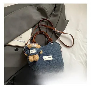 Gros plan sur le tissu denim bleu avec poignée en cuir et breloque ourson