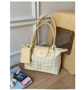 Detail of yellow checkered tote bag featuring cake embroidery and matching small coin pouch