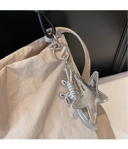 Close-up of a silver star and balloon dog charm hanging on a beige canvas tote bag