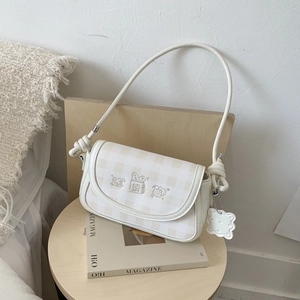 Detail of checkered shoulder bag with cute cartoon embroidery and decorative knot handle