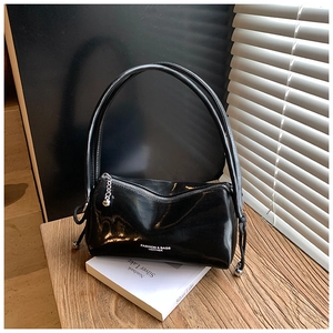 Detail of black patent leather cylinder bag with glossy finish and silver sphere zipper