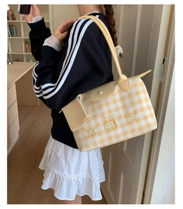 Detail view of yellow plaid tote bag featuring cartoon embroidery and mini zipper pouch