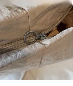 Detail of canvas bag featuring smooth silver ring zipper and textured beige fabric