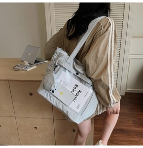 Detail of grey canvas tote bag featuring a transparent PVC front pocket and mini purse