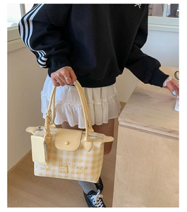 Detail of yellow checkered tote bag with cartoon embroidery and small hanging pouch