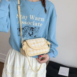 Detail showing a yellow checkered crossbody bag with cute cartoon dog illustration