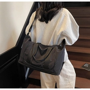 Gros plan du sac de voyage noir avec compartiment inférieur et bandoulière sur escalier