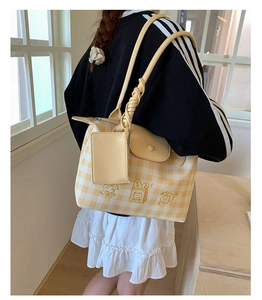 Detail of yellow plaid tote bag with dessert embroidery and spiral woven handle