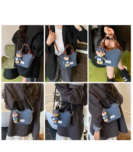 Sac seau en denim avec garniture en cuir et breloque ours dans diverses positions
