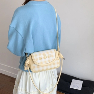 Detail of yellow checkered crossbody bag with cartoon embroidery and knotted strap