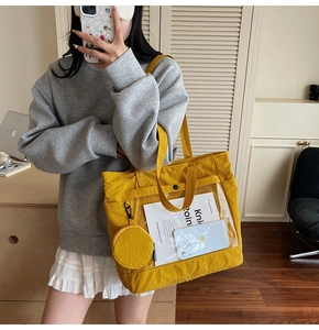Detail of yellow canvas tote bag with large transparent PVC pocket and round coin purse