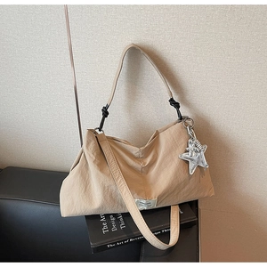 Detail of beige pleated canvas tote with SWAGGER label and silver star charm detail