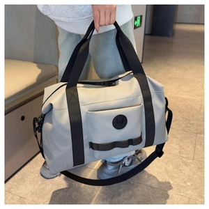 Detail of grey travel duffel bag with black handles and detachable shoulder strap