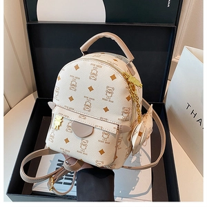 Detail view of mini white bear pattern backpack with golden bear charm in a black gift box