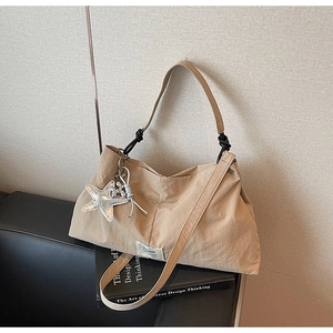 Detail of khaki pleated shoulder bag with silver starfish charm on a design book
