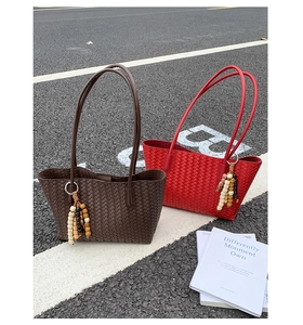 Close-up of woven checkerboard tote bags in brown and red with beaded tassel charms