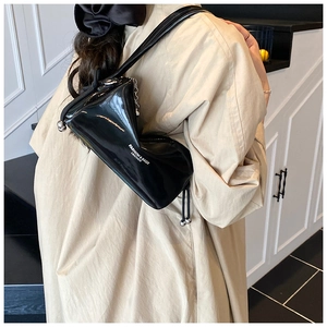 Detail of glossy black leather shoulder bag with white lettering and metal ball zipper