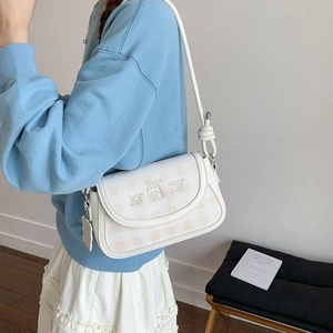 Detail of checkered cream shoulder bag with cute cartoon embroidery and magnetic flap
