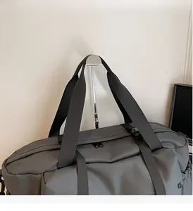Détail du sac de sport gris foncé avec poignées renforcées et tissu en nylon