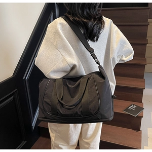 Sac de voyage en nylon noir porté par un mannequin, montrant la capacité et la sangle