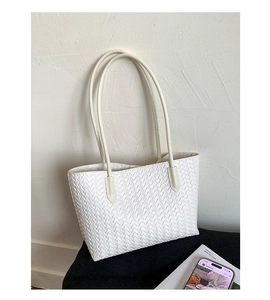 Close-up of white woven tote bag with classic square grid pattern and sleek leather straps