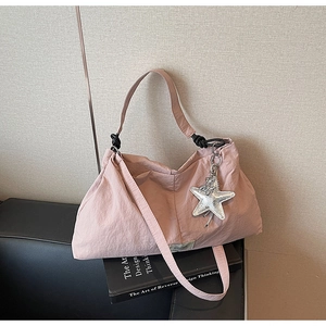 Detail of pink pleated canvas tote bag featuring silver star charm and black knot shoulder strap