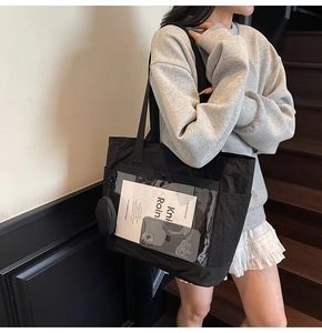 Close-up of black canvas tote bag with clear PVC front pocket and detachable coin purse