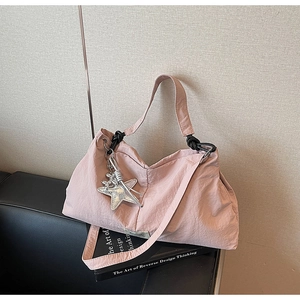 Detail of pink canvas tote bag with black rope handle and silver star charm on sofa