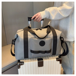Detail view of light grey travel bag with luggage strap fixed on a white suitcase handle