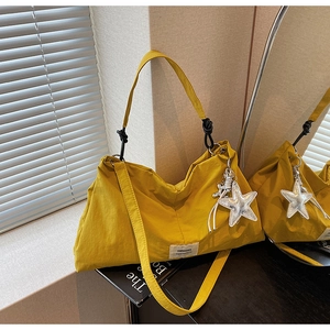 Detail of yellow canvas tote bag with star charm and SWAGGER woven label on black stand