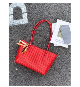 Close-up of red woven tote bag featuring a checkerboard pattern and beaded wood pendant