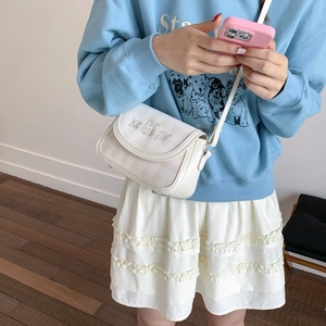 Detail of white checkered crossbody bag featuring cute cartoon animal character patches