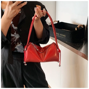 Detail of red faux leather handbag featuring silver metal charms and logo print
