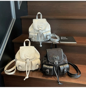 Detail view of mini backpacks in black and cream featuring 3D bow and silver studs
