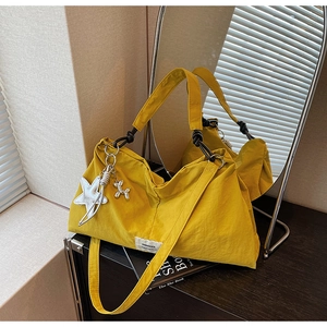 Detail of yellow nylon tote bag with star charm and black knotted handle reflecting in mirror