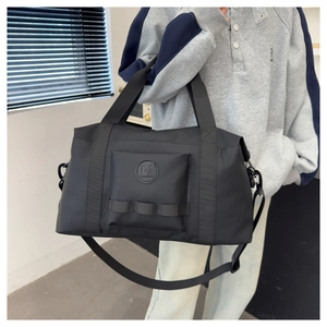 Close-up of black nylon travel bag with wide webbing handles and round leather logo
