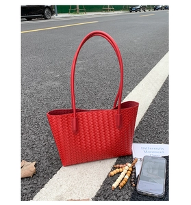 Detail of red woven leather tote bag showing intricate texture and twin slim shoulder straps