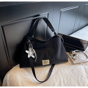 Detail of black canvas tote bag with Swagger label and silver star pendant accessory