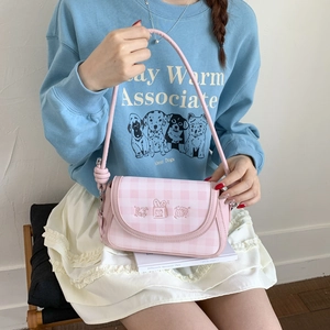 Close-up of pink checkered shoulder bag with cute cartoon embroidery and crossbody strap
