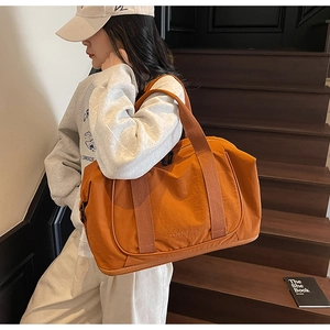 Détail d'un sac de voyage orange en nylon imperméable avec de larges anses en toile