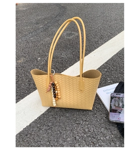 Detail of yellow woven tote bag with bohemian beaded tassel and long shoulder straps