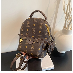 Detail of a brown mini backpack featuring KEDDY BEAR print and golden bear charm