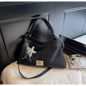Close-up of black canvas tote bag with Swagger label, star charm, and lifestyle props