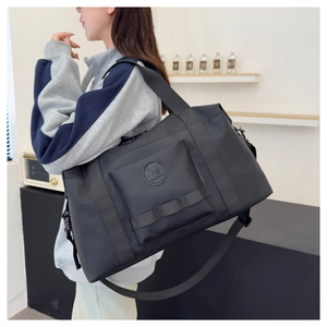 Detail of travel bag with circular logo, reinforced handle and adjustable shoulder strap