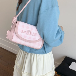 Detail view of pink gingham flap bag with cute embroidery and biscuit pendant